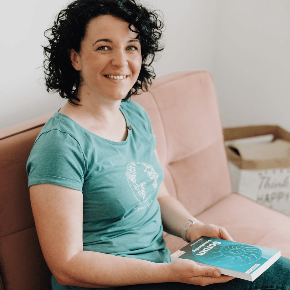 Paulina Hornbachner sitzt auf einer Couch und hält ein Buch.